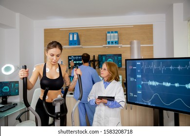Female athlete doing physical effort on stepper and doctor with tablet in hand pursues her. Sports tests