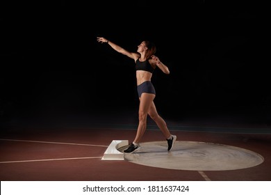 Female athlete doing a shot-put throw, black background. - Powered by Shutterstock