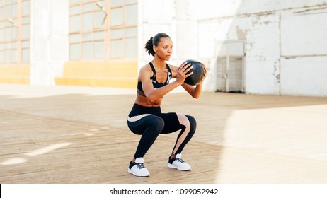 Female athlete doing squat exercises with medicine ball