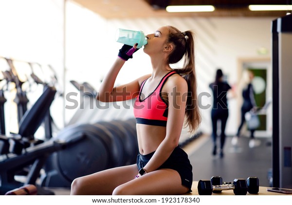 Female athlete drinks water during\
cardio training in the gym. Healthy lifestyle\
motivation