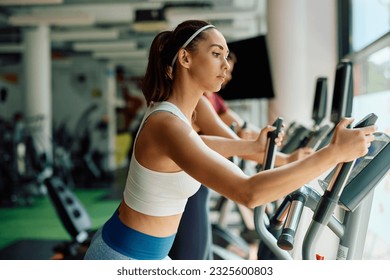 Female athlete exercising on cross trainer during sports training in a gym. - Powered by Shutterstock