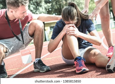 Female Athlete Getting Injured During Athletic Run Training - Male Coach Taking Care On Sport Pupil After Physical Accident - Team Concept With Young Sporty People Facing Mishaps Casualty