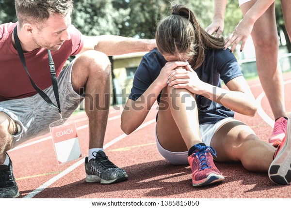 Female
athlete getting injured during athletic run training - Male coach
taking care on sport pupil after physical accident - Team concept
with young sporty people facing mishaps
casualty