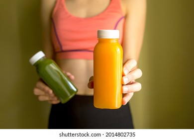A female athlete holds bottles of freshly squeezed vegetable or fruit juice in her hands. The concept of a healthy lifestyle, a healthy body