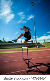 Female athlete jumping above the hurdle during the race - Shutterstock ID 447668464