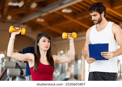 Female athlete lifting weights with coach monitoring progress - Powered by Shutterstock