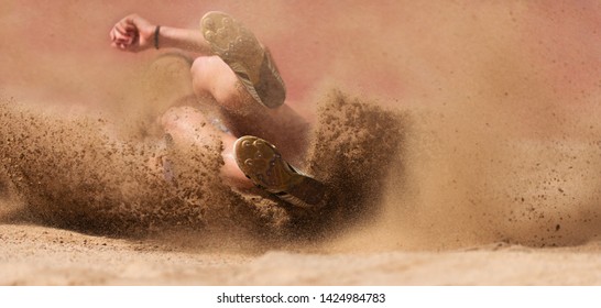 Female Athlete Long Jump Landing Sand Spray