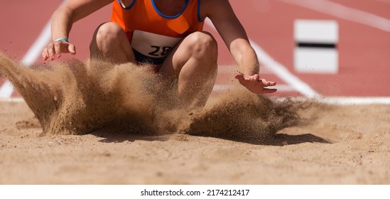 Female athlete long jump landing sand spray, landing in long jump in track and field - Powered by Shutterstock