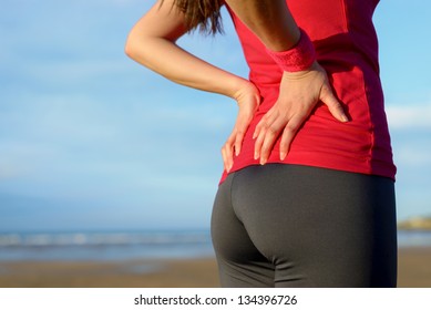 Female Athlete Lower Back Painful Injury. Caucasian Fitness Girl Gripping Her Lowerback Because Sport Injury After Exercising And Running.