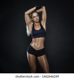 Female athlete on black background Shot of a strong woman with muscular abdomen in sportswear. Fitness female model on black background. Beautiful woman with clean and glowing skin doing stretching.