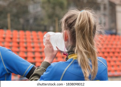 Female athlete on the field drinks water from a bottle. Woman rugby player on the stadium - Powered by Shutterstock