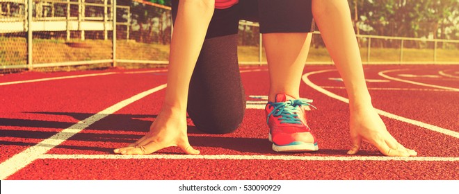 Female Athlete On The Starting Line Of A Stadium Track Preparing For A Run