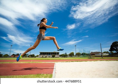 Female athlete performing a long jump during a competition - Powered by Shutterstock