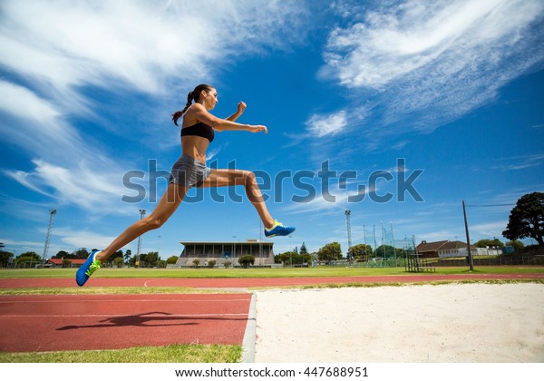 Female athlete performing a long jump during\
a competition