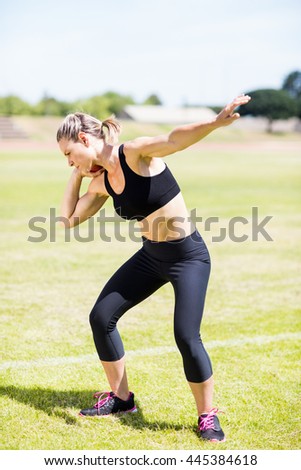 Female athlete preparing to throw shot put ball in stadium