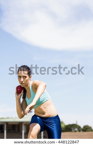 Female athlete preparing to throw shot put ball in stadium