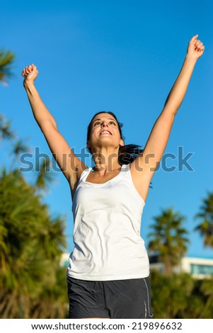 Female athlete running and raising arms for celebrating challenge victory. Woman achieving exercising and sport goals.