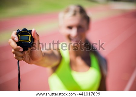 Female athlete showing stop watch on running track