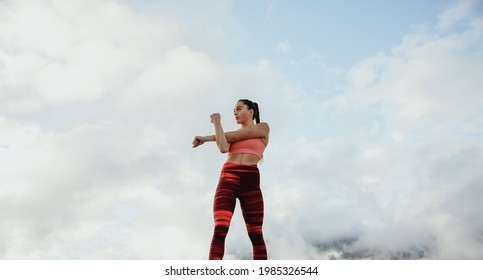 Female athlete in sportswear doing warm up exercise. Sportswoman doing stretching outdoors.