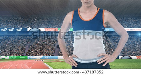 Female athlete standing with hand on hip against view of a stadium