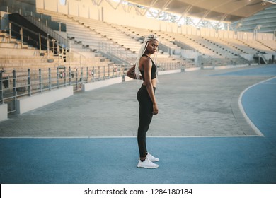 Female Athlete Standing Inside A Track And Field Stadium Ready. Female Runner Getting Ready To Warm Up And Workout Before Running.