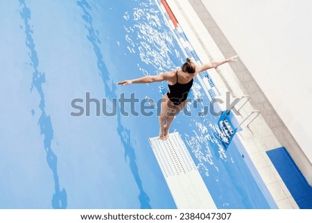 female athlete stands on a springboard, diving competition