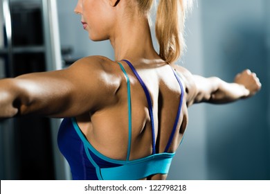 female athlete straining back muscles and arms, do sport in the fitness club