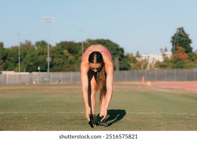 Female athlete stretching hamstrings on grass field - Powered by Shutterstock