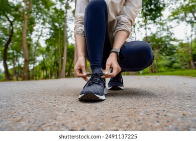 Female athlete tying shoelaces at the park - Powered by Shutterstock