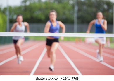 Female Athletes Racing Towards Finish Line At Track Field