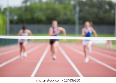 Female Athletes Running Towards Finish Line On Track Field
