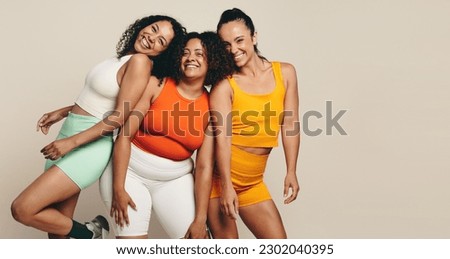 Female athletes smiling at the camera as they stand together in a studio, wearing fitness clothing. Group of young sports women expressing their love for sport, exercise and a health lifestyle. Stock foto © 
