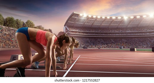 Female athletes sprinting. Three women in sport clothes on starting line prepares to run at the running track in professional stadium - Powered by Shutterstock