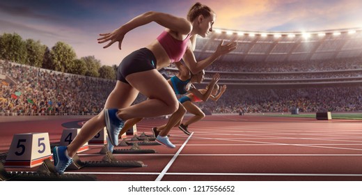 Female athletes sprinting. Three women in sport clothes run at the running track in professional stadium