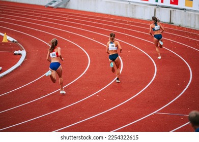 Female athletes at the starting line of a 400m race on track, showcasing their focus and determination as they prepare to compete - Powered by Shutterstock