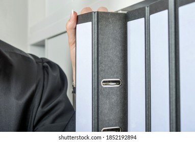 Female Attorney in a robe with folders of files for a case out of the cabinet of her law firm - selective focus