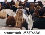 Female audience at the symposyum meeting, participants attendees in conference room hall listens to lecturer, group of women on a congress together listen to speaker on a stage at master-class