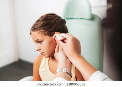 Female Audiologist Examining Girl Ear Using Otoscope In Doctors Office. Child Receiving A Ear Exam. Nose And Throat Medical Examination. Healthcare And Medicine Concept. 