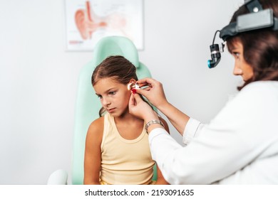 Female Audiologist Examining Girl Ear Using Otoscope In Doctors Office. Child Receiving A Ear Exam. Nose And Throat Medical Examination. Healthcare And Medicine Concept. 