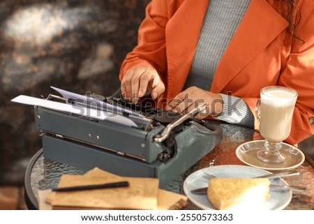 Female author using typewriter at table in street cafe, closeup