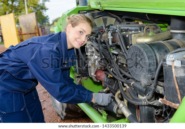 female\
auto mechanic fixing the engine of a car\
outdoors