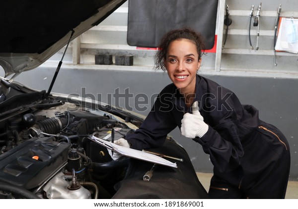Female auto\
mechanic giving thumb up at garage, car service technician checking\
and repairing the customer’s car at automobile service center,\
vehicle repair service shop\
concept.