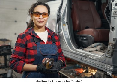 Female auto mechanic with grinder tool standing in garage - Powered by Shutterstock