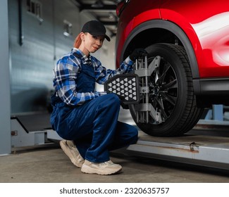 A female auto mechanic makes a camber. Woman working in a car service. - Powered by Shutterstock