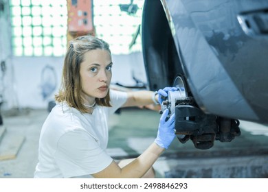 female auto mechanic repairs car brake system - Powered by Shutterstock