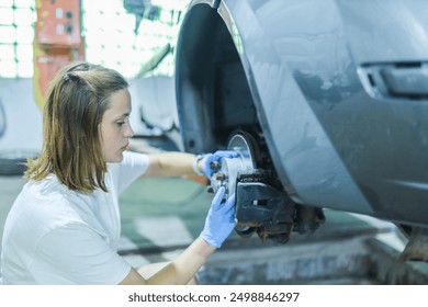 female auto mechanic repairs car brake system - Powered by Shutterstock