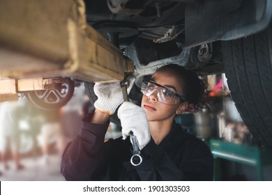 Female auto mechanic work in garage, car service technician woman check and repair customer car at automobile service center, inspecting car under body and suspension system, vehicle repair  shop.