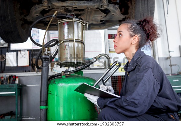 Female auto mechanic work in garage, car service\
technician woman check and repair customer car at automobile\
service center, inspecting car under body and suspension system,\
vehicle repair  shop.