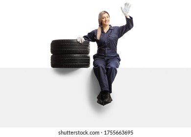 Female auto mechanic worker in a uniform sitting on a panel with tires and waving isolated on white background - Powered by Shutterstock