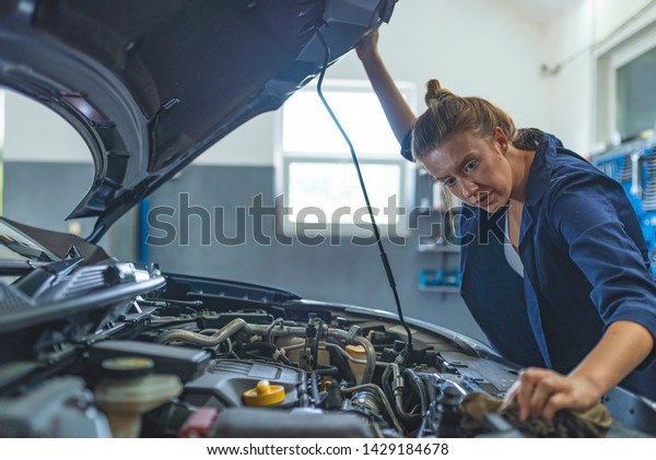 Female Auto mechanic working in\
garage. Repair service. Woman with dirty hands fixing the car.\
Getting her car back on the road. Mechanic working in his\
workshop